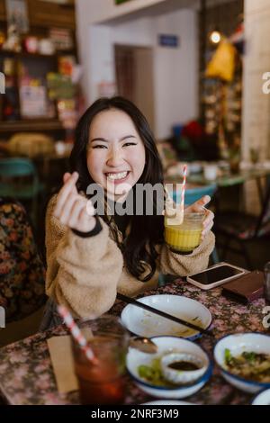 Eine glückliche Frau, die im Restaurant ein Getränk in der Hand hält Stockfoto
