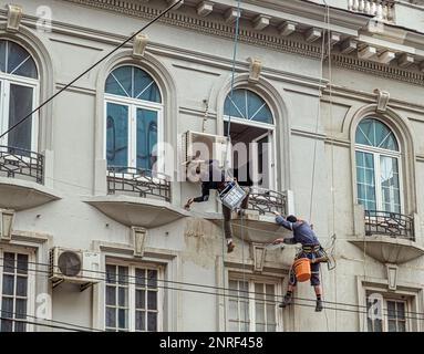Bukarest, Rumänien - 21. Februar 2023. Industrialpinist in der Höhe am Seil, Putzwand mit Kelle. Reparaturhaus für Industrietechniker f Stockfoto