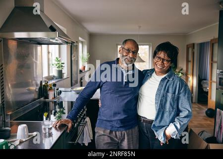 Porträt eines glücklichen Seniorenpaares, das zu Hause in der Küche steht Stockfoto