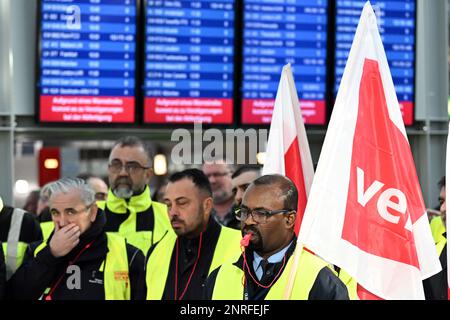 Düsseldorf, Deutschland. 27. Februar 2023. Streikende Flughafenangestellte stehen mit Verdi-Flaggen im Flughafenterminal. Die Gewerkschaft Verdi hat ihre Mitglieder aufgefordert, auf Flughäfen in Nordrhein-Westfalen und im öffentlichen Sektor Warnstreiks zu Unternehmen. Kredit: Federico Gambarini/dpa/Alamy Live News Stockfoto