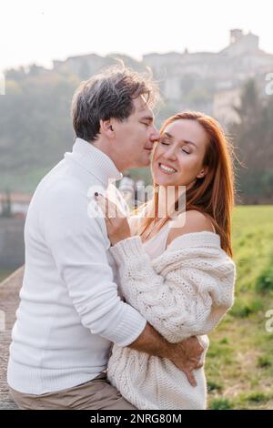 Ein liebevolles Paar umarmt sich, ein Mann küsst sanft eine Frau Stockfoto