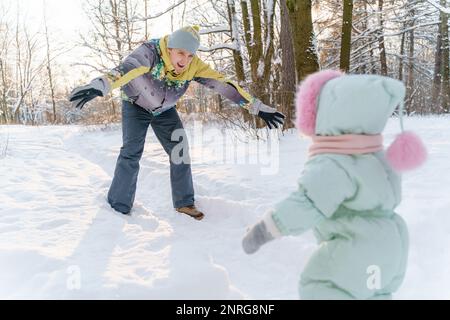 Vater und eine einjährige Tochter machen einen Spaziergang in einem verschneiten Park Stockfoto