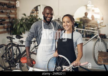 Sieh zu, wie wir glühen, zweifle an unserem Wachstum. Porträt von zwei Kollegen, die ein Motorrad in einer Fahrradwerkstatt reparieren. Stockfoto