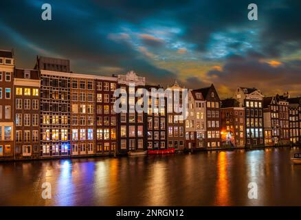 Typische Häuser am Damrak bei Nacht, in Amsterdam, Niederlande Stockfoto
