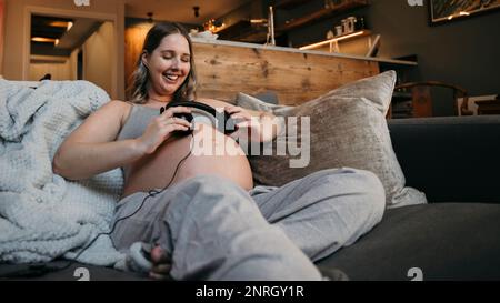 Nahaufnahme der Mutter, die auf ihrem Sofa lacht und Musik hört. Stockfoto