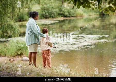 Rückblick auf Mutter und Tochter, die gemeinsam am See angeln, in einem schönen Moment der Familie, Kopierbereich Stockfoto