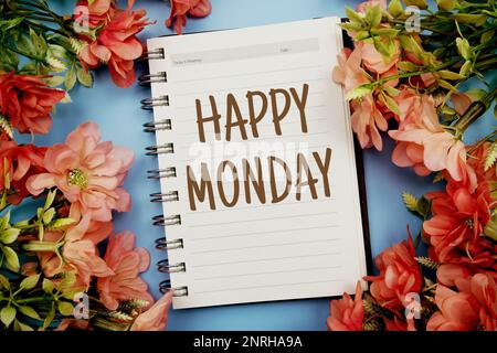 Happy Monday Typografie Text auf Papier Notizbuch flach auf blauem Hintergrund Stockfoto