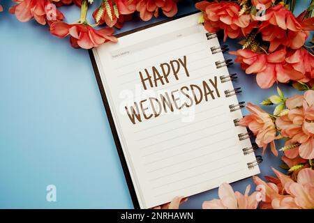 Happy Wednesday Typografie Text auf Papier Notizbuch flach auf blauem Hintergrund Stockfoto