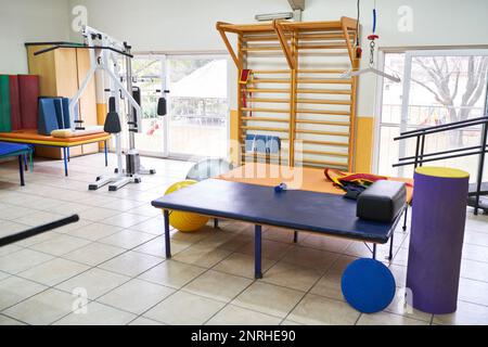 Das Innere des Rehabilitationszentrums mit verschiedenen Trainingsgeräten und Bett im Zimmer Stockfoto