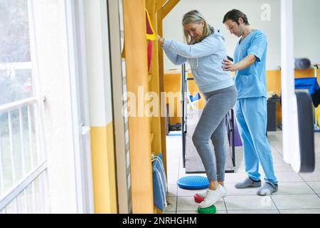 Seniorin mit männlichem Physiotherapeut, der in der Reha trainiert Stockfoto