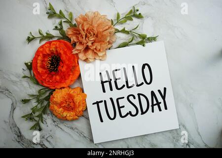 „Hello Tuesday“-Text mit orangefarbenem Blumenstrauß auf Marmorhintergrund Stockfoto