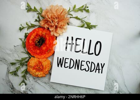 „Hallo Mittwoch“-Text mit orangefarbenem Blumenstrauß auf Marmorhintergrund Stockfoto