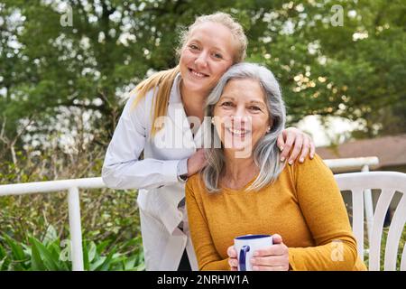 Porträt einer glücklichen Ärztin mit Seniorin im Garten des Pflegeheims Stockfoto