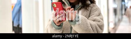 Frau, die ihr Handy benutzt, während sie im Einkaufszentrum steht. Stockfoto