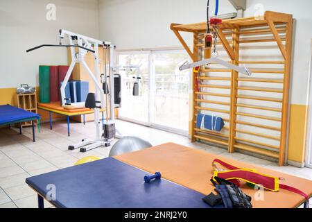 Leeres Bett und verschiedene Trainingsgeräte im Zimmer des Rehabilitationszentrums Stockfoto