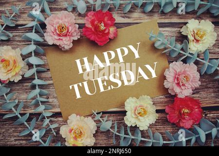 Happy Tuesday Typografie Text auf Papierkarte dekorieren Sie mit Blumen auf Holzhintergrund Stockfoto