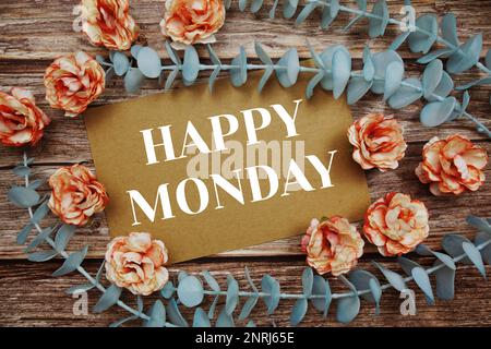 Happy Monday Typografie Text auf Papierkarte dekorieren Sie mit Blumen auf Holzhintergrund Stockfoto