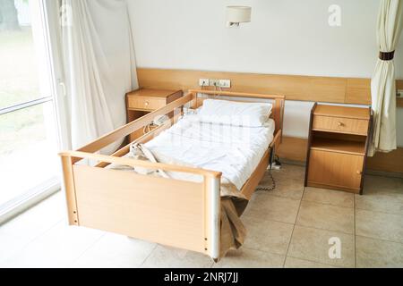 Aus einem hohen Blickwinkel weißes Laken und Kissen auf leerem Bett im Pflegeheim Stockfoto