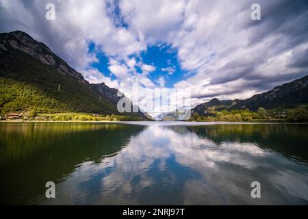 Landschaft mit Bergen, Berghängen, Wäldern und Wolken, die sich auf der Oberfläche des Sees Lago d'Idro spiegeln. Stockfoto