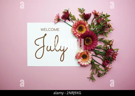 Willkommenstext im Juli mit Blumen auf pinkfarbenem Hintergrund Stockfoto