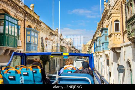 Fahrt durch Malta mit Hop-on-Hop-off-Sightseeing-Bus. Wunderschöne Altstadt in Malta mit traditionellem farbenfrohem maltesischen Holzbalkon, der Gallarija. Stockfoto