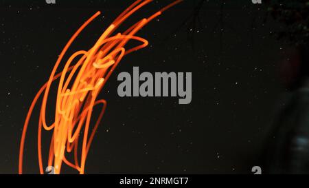 Rote Funkenspuren von einem Feuer am Sternenhimmel. Stockfoto