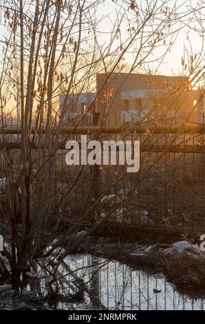 Der Müll taute im Frühling aus dem Schnee bei Sonnenuntergang auf der Straße in Russland auf Stockfoto