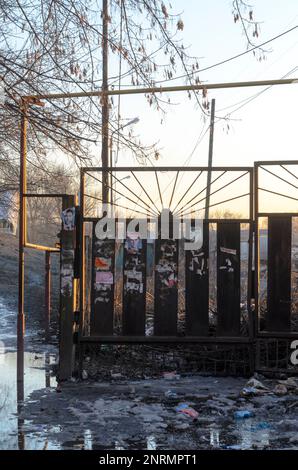 Der Müll taute im Frühling aus dem Schnee bei Sonnenuntergang auf der Straße in Russland auf Stockfoto