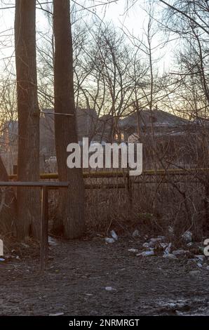 Der Müll taute im Frühling aus dem Schnee bei Sonnenuntergang auf der Straße in Russland auf Stockfoto