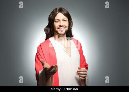 Jesus Christus streckt seine Hand auf grauem Hintergrund aus Stockfoto