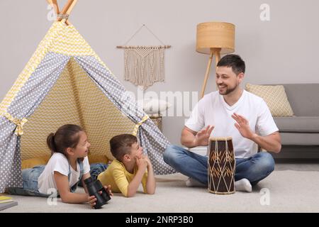 Vater und Kinder, die zu Hause in der Nähe von Wigwam spielen Stockfoto