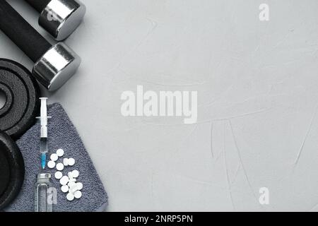 Verschiedene Drogen und Sportgeräte auf grauem Hintergrund, flach liegend mit Platz für Text. Dopingkontrolle Stockfoto