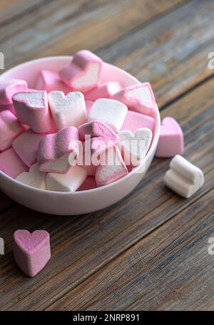 Schüssel mit Marshmallows in Form von Herzen, Nahaufnahme auf Holzhintergrund. Stockfoto