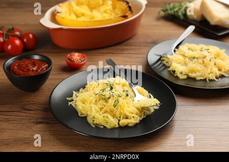 Leckerer Spaghetti-Kürbis mit Thymian und Käse auf einem Holztisch Stockfoto