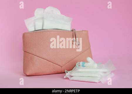 Beutel mit Menstruationseinlagen und Tampons auf pinkfarbenem Hintergrund Stockfoto
