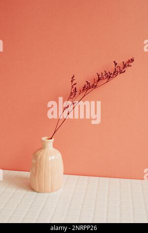 Vase aus rosa trockener Blume auf weißem Tisch. Rosafarbener Wandhintergrund. Inneneinrichtung Stockfoto