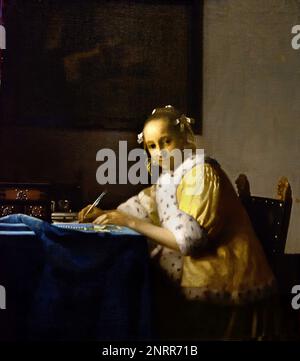 A Lady writing 1664-1667 von Johannes Vermeer oder Jan Vermeer 1632 - 1675, Delft, Niederlande, Holländisch, Holland, (Holländischer Maler im Goldenen Zeitalter, einer der größten Maler des 17. Jahrhunderts. Bevorzugte zeitlose, gedämpfte Momente, bleibt rätselhaft, unnachahmliches Farbschema und verwirrender Lichtinhalt) Stockfoto