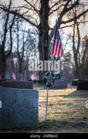 Die Sonne geht auf amerikanischen Flaggen und Weihnachtskränzen auf einem Friedhof in Wisconsin auf. Stockfoto