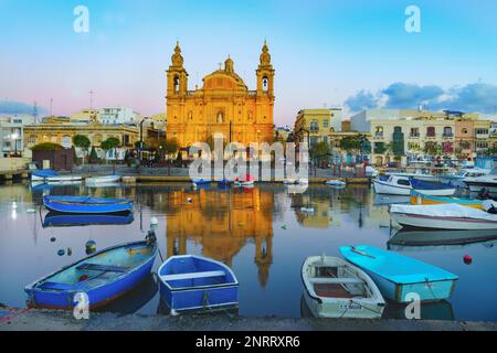 Msida, Malta, 22. November 2017 Parish Church of Saint Joseph (1889) bei Sonnenaufgang. Traditionelle blaue maltesische Boote im Vordergrund. Stockfoto
