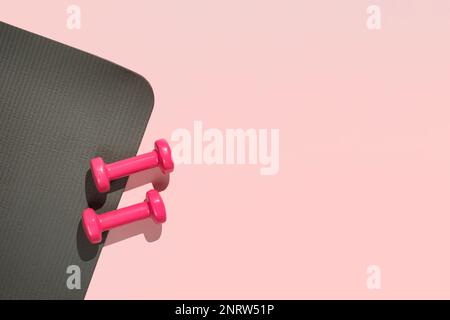 Stylisches Fitness-Training in Grau und Pink und Flat Lay im Fitnessstudio. Draufsicht auf graue Sportmatte und rosa Kurzhanteln auf rosa Hintergrund. Set für Pilates, Fitness mit Kopierplatz Stockfoto