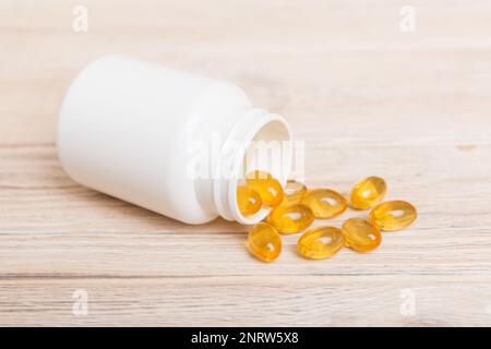 Omega-3 Kapseln liegen in einer weißen Flasche auf einem Tischhintergrund. Fischöl Tabletten Draufsicht. Biologisch aktive Zusatzstoffe. omega 6, Omega 9, Vitamin A, E, Stockfoto