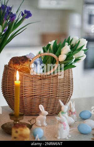 osterkuchen und Kaninchen auf dem Hintergrund eines Korbs mit weißen Tulpen. Innen, Küche. Hochwertiges Foto Stockfoto