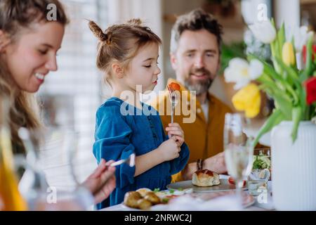 Glückliche junge Familie, die zusammen zu Ostern isst. Stockfoto