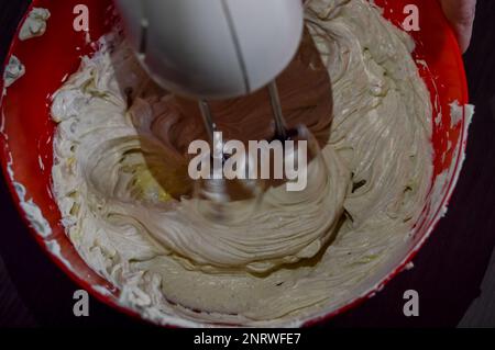 Mixer mischt frischen Weißkäse und Eier zu Käsekuchen-Sahne Stockfoto