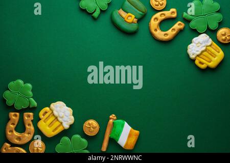 Banner für St. Patrick's Day auf grünem Hintergrund. Münzen, Hufeisen, vierblättriges Kleeblatt als Symbol des Feiertags. Platz für Text. Lebkuchenkeks Stockfoto