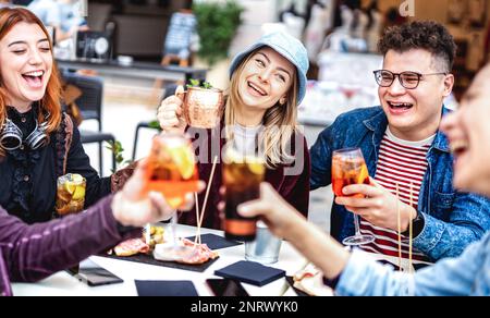 Trendige Freunde toasten in einem schicken Restaurant draußen - Lifestyle-Konzept mit jungen Leuten, die sich zur Happy Hour auf dem Bürgersteig amüsieren Stockfoto