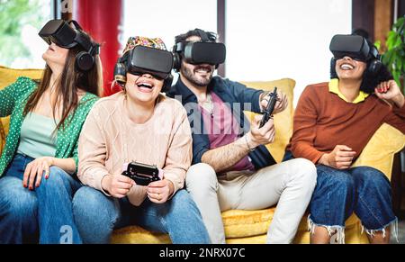 Trendige Leute, die mit einer VR-Brille auf dem Sofa spielen – Virtuelle Realität und am Körper tragbares Technologiekonzept mit Mitbewohnerfreunden, die Spaß mit einer Headset-Brille haben – Gene Stockfoto