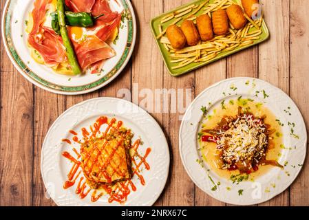 Auswahl an Gerichten mit Ceredtas spanischer Tapas mit Kroketten, iberischem Schinken mit wildem Spargel und Spiegeleiern Stockfoto