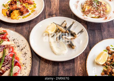 Auswahl an Gerichten mit spanischen Tapas-Rezepten mit gebratenen Sardellen, gegrilltem Oktopus, Ventresca-Salat und Criadillas Stockfoto