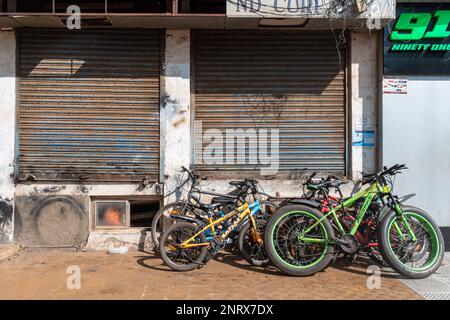 Panjim, Goa, Indien - Januar 2023: Fahrräder parken auf einem Gehweg vor den geschlossenen Geschäften eines Marktes in der Stadt. Stockfoto